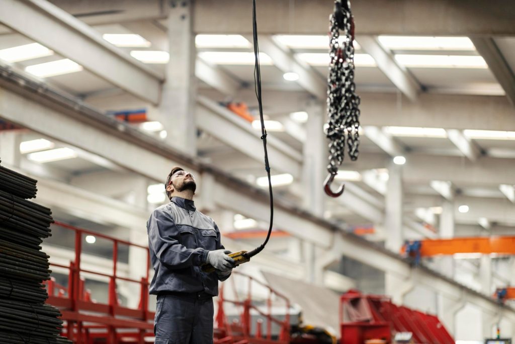 Medewerker bedient een kraan bij het hijsen van een last in een productiehal